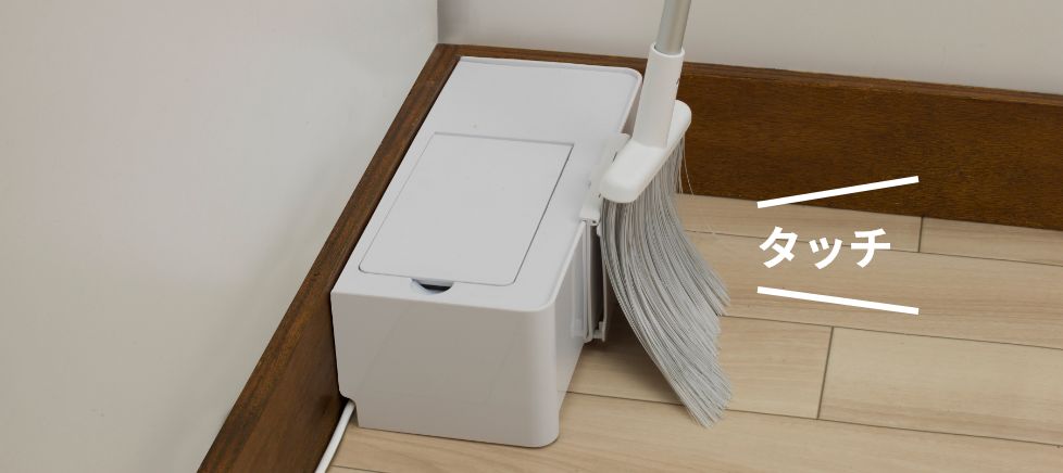 ほうきで本体のスイッチにタッチしているようす